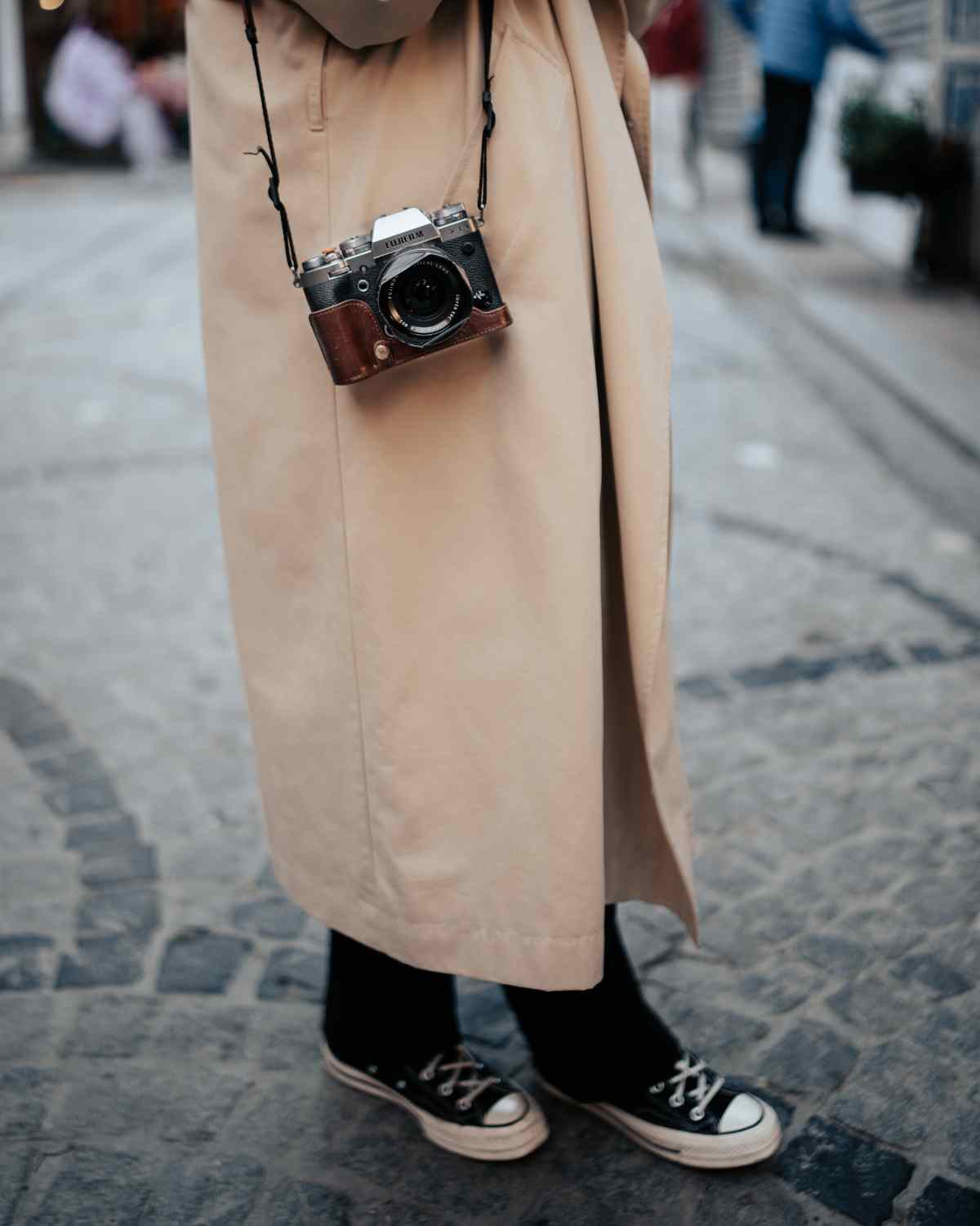 Giovane con macchina fotografica vintage al collo e sneakers, simbolo di sguardo fresco e nuovi punti di vista