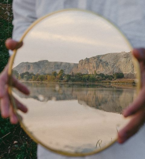 Specchio che riflette un paesaggio naturale, simbolo di introspezione, riflessione e apprendimento trasformativo